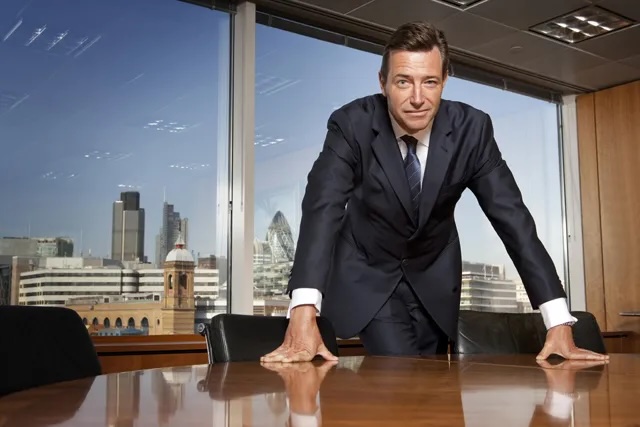 Portrait of John Ridding, CEO of Financial Times Group, discussing the FT's strategic approach to AI partnerships. His quote emphasizes the importance of being inside the development loop as content discovery evolves, representing forward-thinking media leadership navigating technological disruption by engaging with rather than resisting transformative AI technologies.